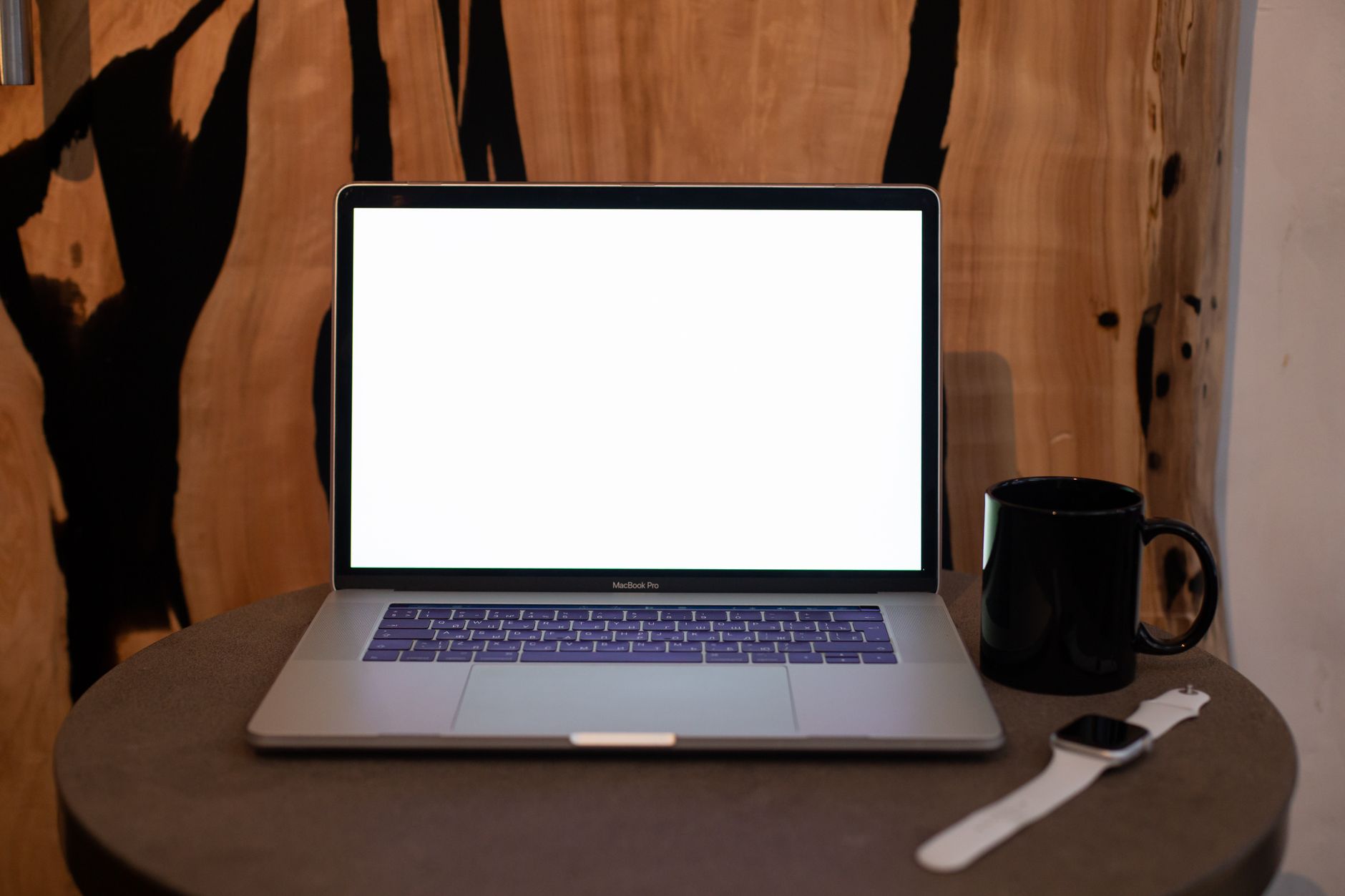 A modern laptop resting on a clean wooden desk in an office setting.